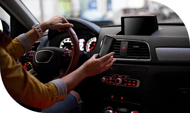 Woman using phone mount inside modern car with dashboard accessories.
